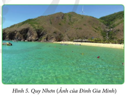 A beach with a sandy beach and a mountain in the background

Description automatically generated